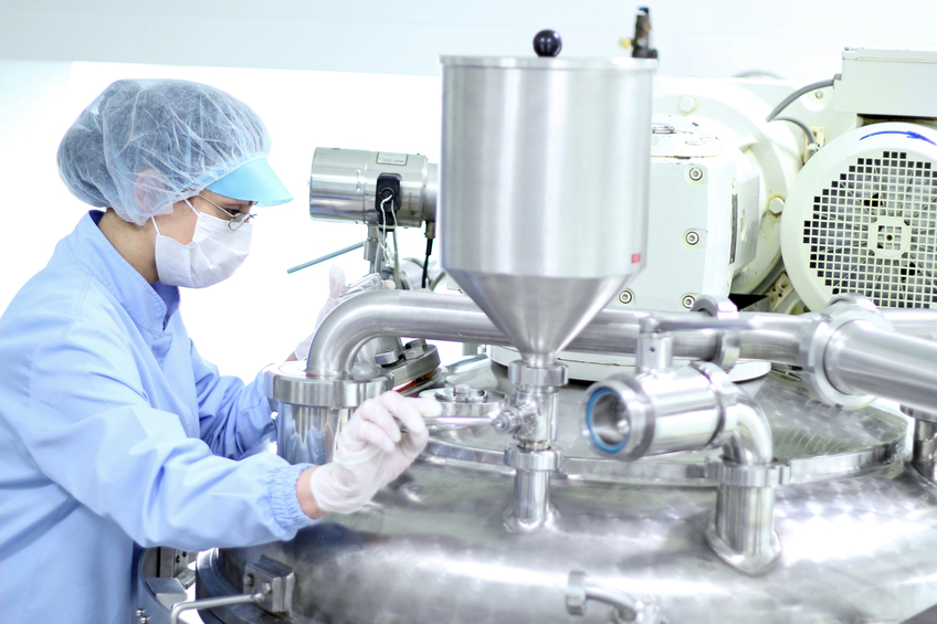 Pharmaceutical worker preparing machine for work in pharmaceutical factory.
