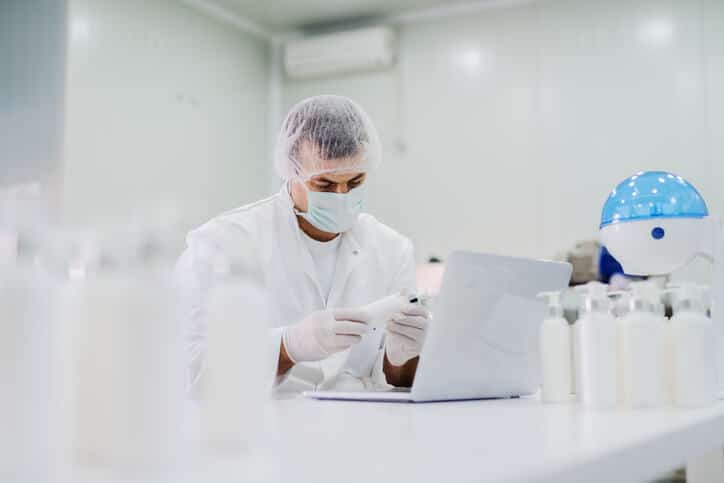 Young regulatory affairs professional sitting in a lab verifying the environmental claims of a cosmetic product.