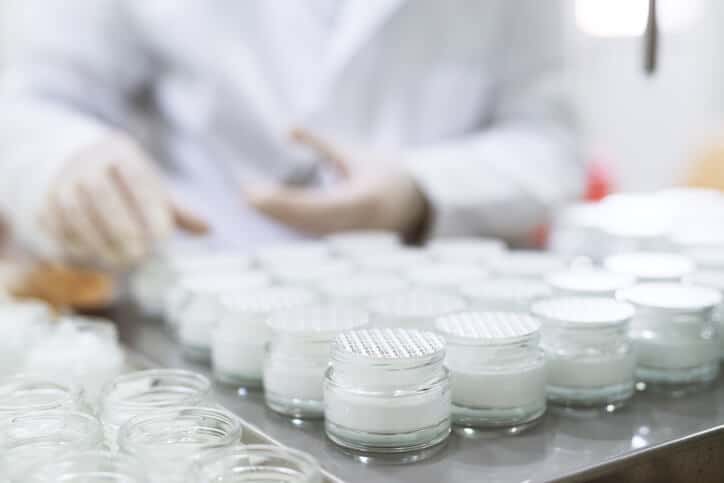 Regulatory affairs professional checking the packaging of face creams in bottles.