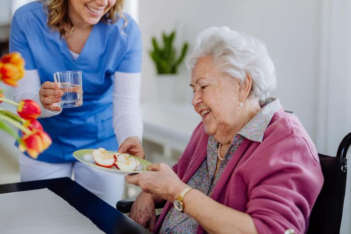 An elderly resident receiving a meal aligned with dietary planning as per food and nutrition training