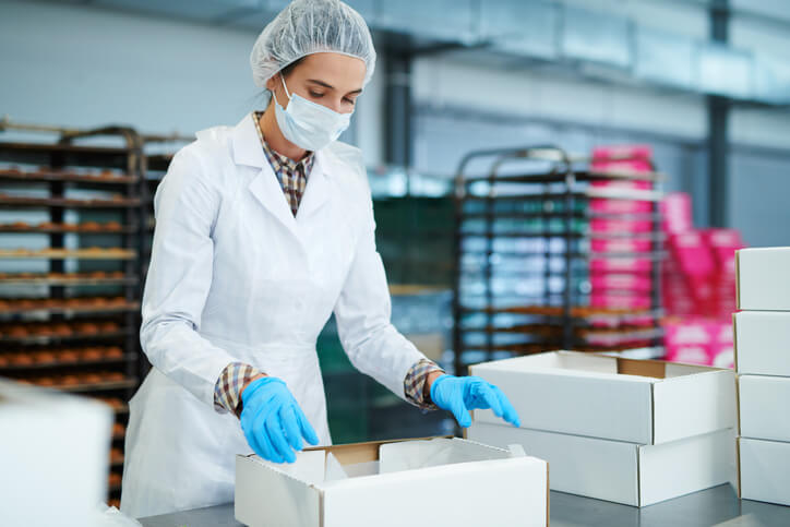 A food quality professional is inspecting packaged food in a manufacturing facility