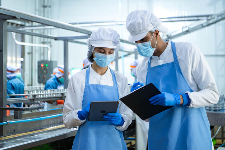A food safety team reviewing compliance documentation in a processing plant