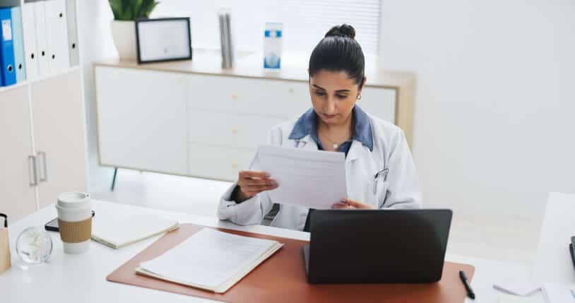 A clinical research associate reviewing source documents against a trial protocol