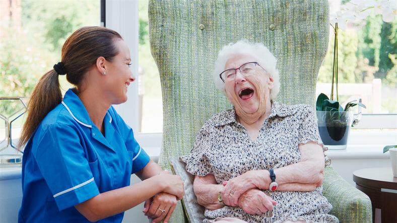 A friendly female personal support worker interacting with an elderly female client