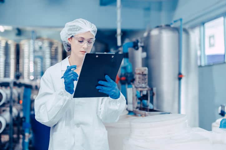 A pharmaceutical quality assurance specialist reviewing batch records in a GMP facility