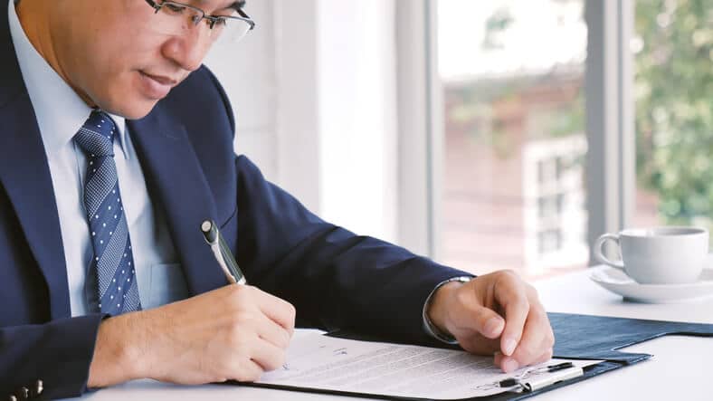 A male regulatory affairs professional completing paperwork in an office after regulatory affairs training.