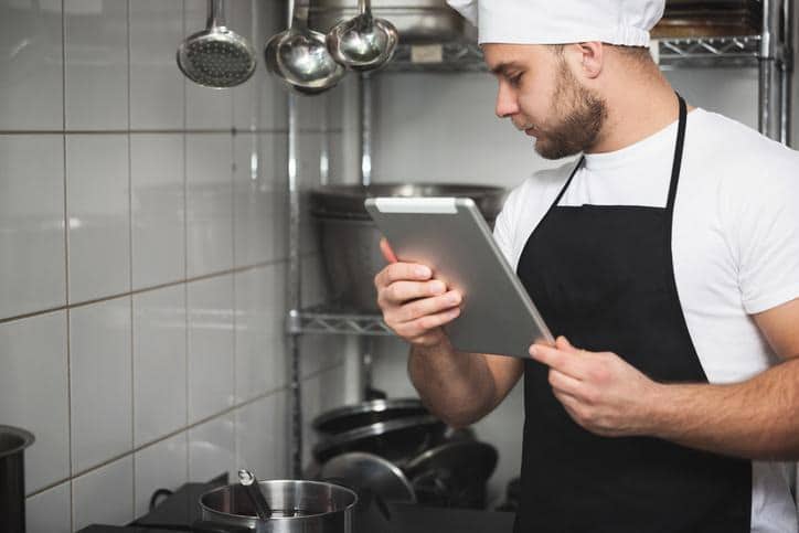 A chef reviewing a tablet in a commercial kitchen